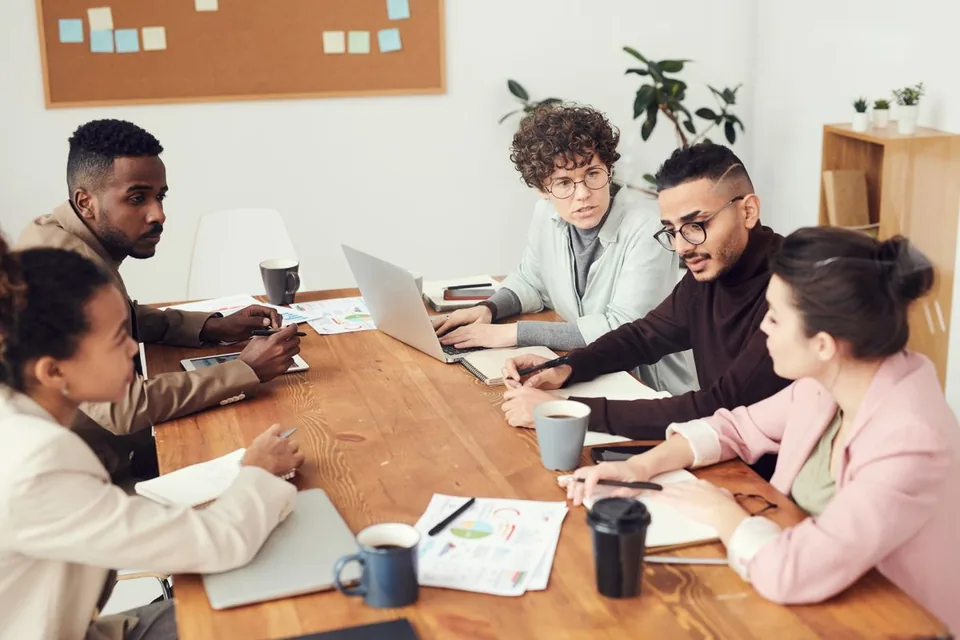 A team discussing documents and a laptop around a work table.