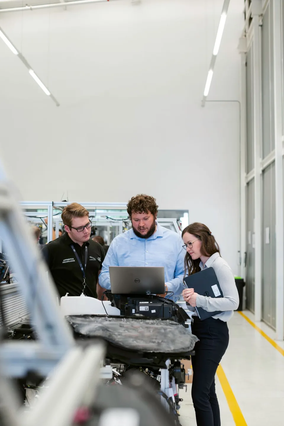 Professionals reviewing a laptop together in an industrial workshop.